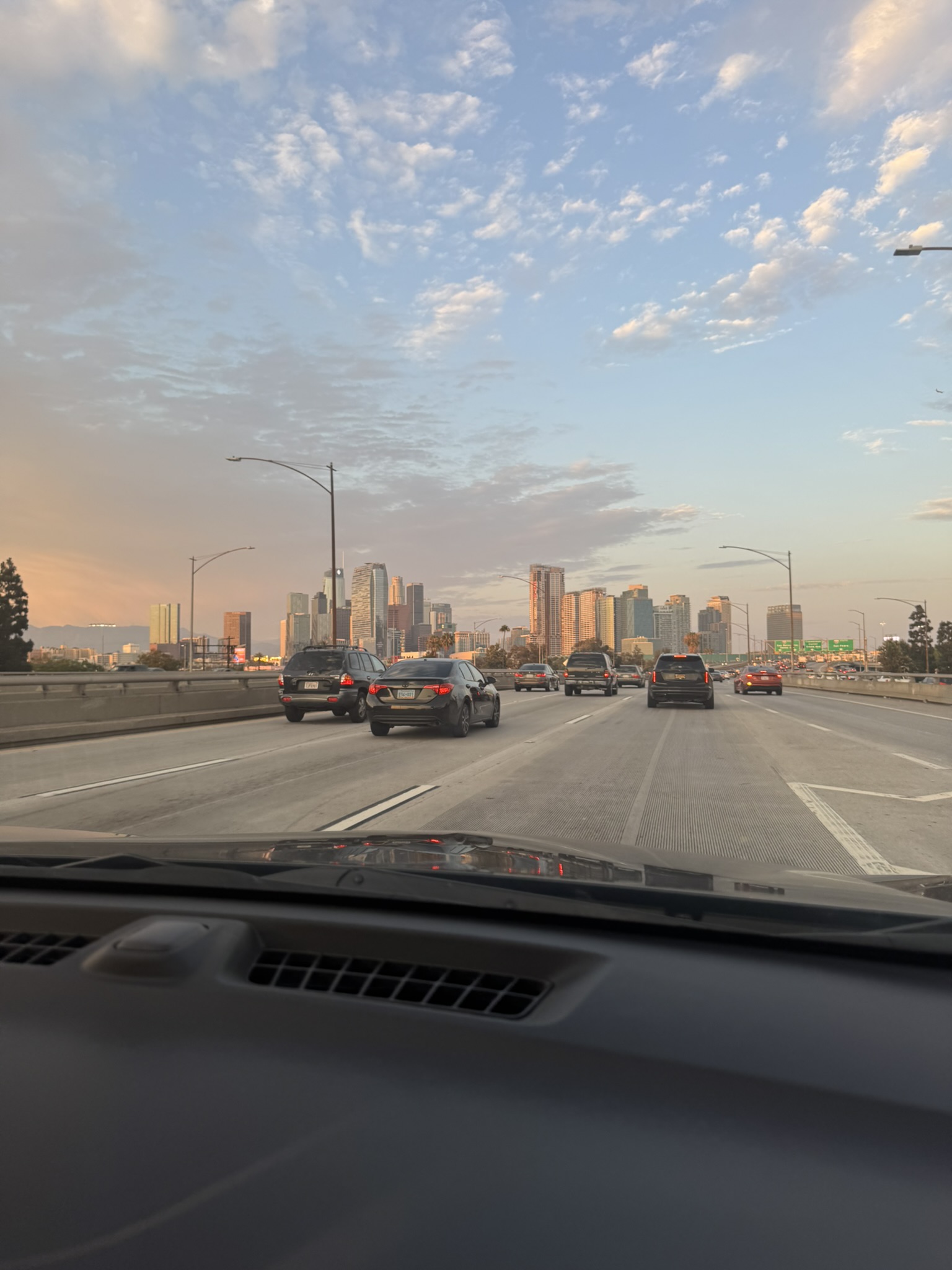 Driving view toward the downtown Los Angeles skyline at sunset